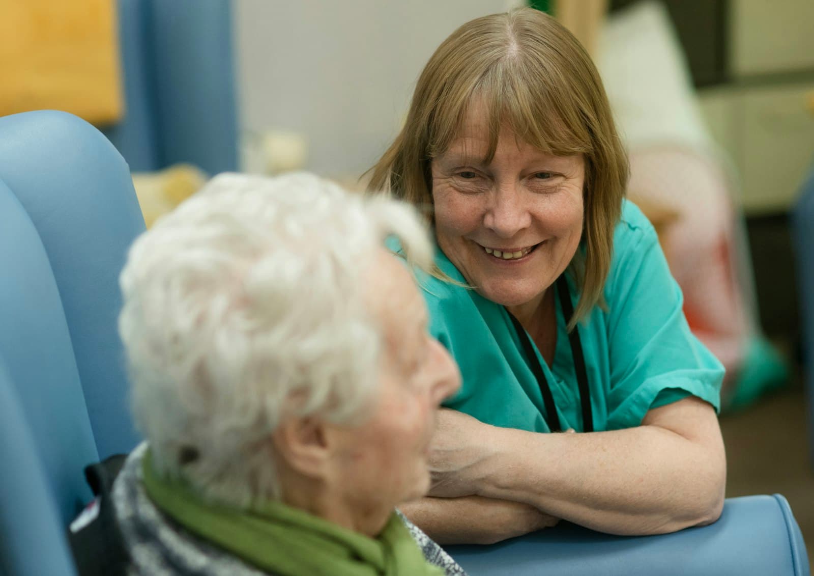 A caregiver holding the hand of an elderly woman at home